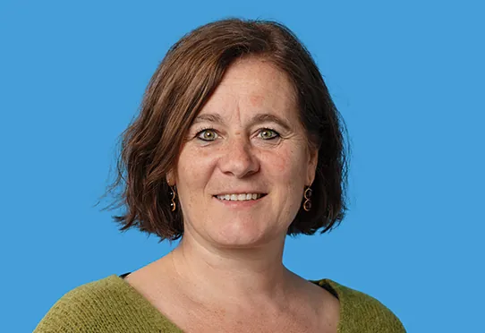 Eine lächelnde Franziska Roth – Co-Präsidentin Dakomed und Ständerätin (SP Solothurn) in grüner Strickjacke vor blauem Hintergrund